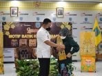 PEMKAB LAMANDAU DIRESMIKAN: Bupati Lamandau H Hendra Lesmana menyerahkan selendang batik motif Lamandau kepada Ketua Dekranasda Lamandau Hj Rusdianti Hendra Lesmana, tanda diluncurkannya sebelas motif batik Lamandau. (FOTO:HUMAS UNTUK KALTENG POS)