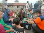 BAWAH-Wabup KUNJUNGAN KERJA: Wabup Kotim, Irawati (pakai masker putih) memastikan kondisi kesehatan warga yang ada di wilayah terdampak banjir, Rabu (15/9). (FOTO: SAMPIT - Pemerintah Kabupaten Kotawaringin Timur terus melakukan upaya preventif terhadap kesehatan warga yang terdampak banjir. Hal itu dilakukan untuk mengetahui kondisi kesehatan, sehingga jika ada penyakit membaha-yakan, warga bisa langsung dirujuk ke fasilitas kesehatan. Wakil Bupati (Wabup) Kotim, Irawati bersama tim BPBD, ketua Ikatan Bidan Indonesia (IBI) memberikan pelayanan kesehatan, dan pengobatan bagi warga yang mengalami ganguan kesehatan di Dusun Muara Ubar, dan Desa Tanah Putih, Kecamatang Telawang, Rabu (15/9). Selain itu, kedatangan mantan anggota DPRD Provinsi Kalteng itu bersama rombongan juga memberikan bantuan so-sial (bansos) berupa sembako kepada masyarakat di dua desa tersebut. “Kemarin saya langsung melihat kondisi kesehatan warga yang terdampak banjir. Saya apresiasi petugas kesehatan di lapangan selalu stanby memberikan pe-layanan kesehatan,” kata Irawati. Dia meminta, agar petugas kesehatan yang berada di lapangan untuk selalu rutin melakukan pemantauan terhadap kondisi warga. Sebab dalam situasi seperti ini tentu sewaktu - waktu sejumlah penyakit seperti demam, diare, dan lain sebagainya, bisa menyerang sehingga sangat penting untuk terus melakukan pemantauan terhadap kondisi kesehatan warga. “Tujuan saya sering turun ke lokasi banjir untuk memastikan kondisi warga, mengingat saat ini masyarakat terdampak sedang mengalami musibah dan sudah selayaknya untuk dibantu serta diperhatikan,” tegasnya. Kepada masyarakat, Irawati beperpesan jika ada keluhan kesehatan bisa segera melapor atau menghubungi petugas kesehatan yang ada di lapangan, untuk bisa dilakukan pelayanan kesehatan dan mari sama - sama berdoa agar masalah ini bisa segera selesai. (sli/ans) )