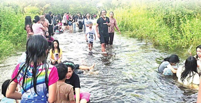 Warga bermain air di jalan Barito Raya Buntok yang terendam banjir