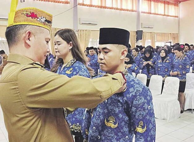 MENYEMATKAN Bupati Gumas, Jaya S Monong saat menyematkan PIN tanda CPNS bagi peserta yang menerima SK di GPU Tampung Penyang, Senin (19/5).