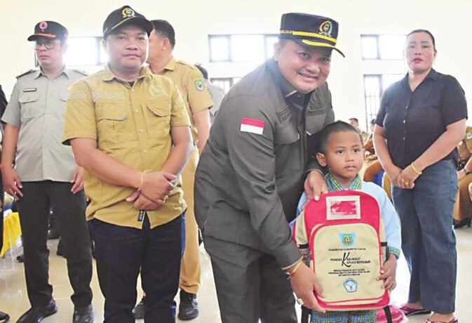 PENDIDIKAN: Ketua DPRD Kapuas Ardiansah didampingi Wakil Ketua II DPRD Kapuas Berinto menyerahkan tas kepada anak saat kunjungan kerja ke Kecamatan kapuas Tengah, Selasa (5/8).