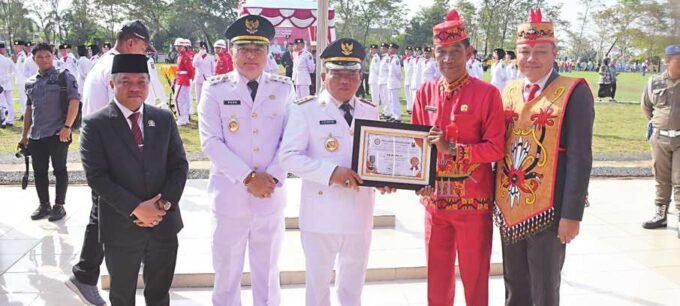 PENGHARGAAN: Bupati Kapuas HM Wiyatno menerima piagam penghargaan sebagai Bupati peduli Radio Tahun 2025 yang diserahkan Kepala Dinas Kominfosantik Kapuas Hartoni U Sawang seusai upacara peringatan HUT ke-80 Kemerdekaan RI di Stadion Olahraga Panunjung Tarung Kuala Kapuas, Minggu (17/8).