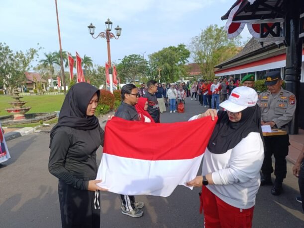 BAGIKAN : Wakil Bupati Kotim, Irawati saat membagikan bendera merah putih secara gratis kepada masyarakat, sekitar area Sekretariat Daerah (Setda) Kotim, Jumat (1/8/2025),