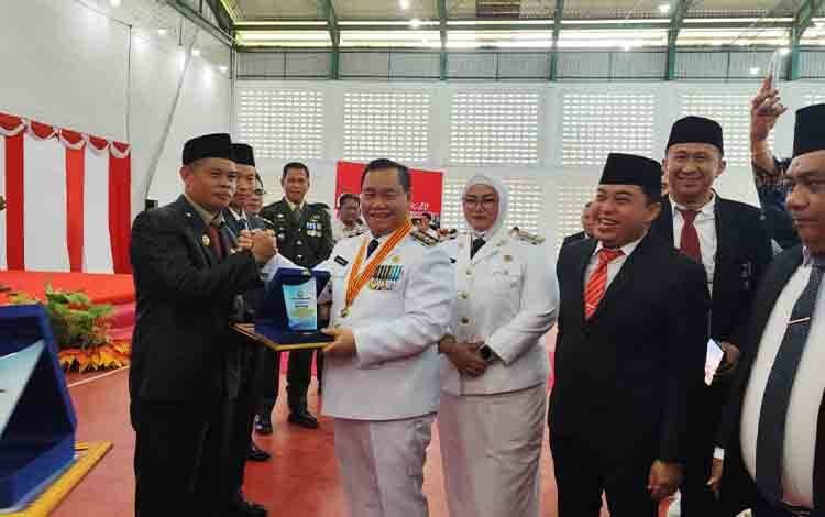 KOTIM PENGHARGAAN : Bupati Kabupaten Kotim H.Halikinnor saat menyerahkan penghargaan kepada Kepala Bapperida Alang Arianto saat ramah tamah di Stadion 29 November Sampit, Minggu (17/8).