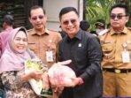 DPRD BATARA SERAHKAN SEMBAKO: Ketua Komisi II DPRD Barito Utara, H Taufik Nugraha menyerahkan sembako kepada warga saat menghadiri operasi pasar murah yang dilaksanakan di area SPBU Perusda Batara Membangun, Senin (15/9).