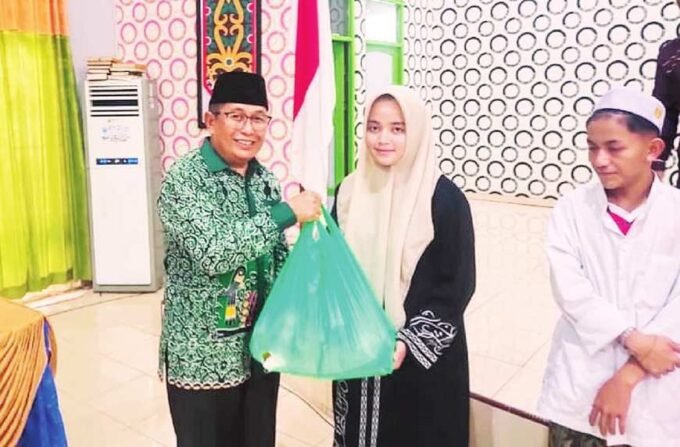 DPRD MURA PENYERAHAN: Ketua Komisi I DPRD Mura, Rejikinoor (kiri) menyerahkan bingkisan saat Lebaran Yatim dan Difabel, Jumat (4/7).