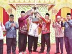 KAPUAS JUARA: Ketua Umum LPTQ Kabupaten Kapuas Dr H Suwarno Muriyat menyerahkan trofi juara umum kepada kafi lan MTQH Kecamatan Pulau Petak, Minggu (7/9).
