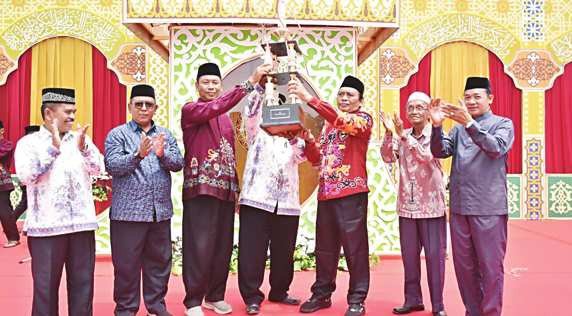 KAPUAS JUARA: Ketua Umum LPTQ Kabupaten Kapuas Dr H Suwarno Muriyat menyerahkan trofi juara umum kepada kafi lan MTQH Kecamatan Pulau Petak, Minggu (7/9).