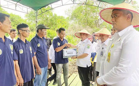 KAPUAS PENYERAHAN PREMI: Wakil Bupati Kapuas Dodo menyerahkan premi secara simbolis kepada salah satu warga binaan rutan pada kegiatam Panen Padi Perdana, di Lahan Pertanian Pulau Petak.