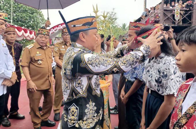 ANGKAT BUDAYA DAERAH: Wakil Ketua II Berinto memasangkan sumping saat pencanangan penggunaan lawung/sumping di lingkungan sekolah pada hari tertentu. Kegiatan berlangsung di Huma Betang Sei Pasah, Senin (8/12) pagi.