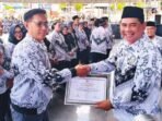 PENGHARGAAN: Bupati Shalahuddin (kanan) menyerahkan sertifikat penghargaan kepada salah satu tenaga pendidik Kecamatan Teweh Timur atas partisipasi pada HUT PGRI dan HGN Tahun 2025 di Arena Terbuka Tiara Batara, Rabu (10/12).