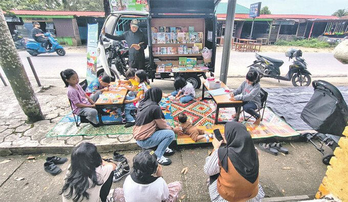 Motor Pustaka Keliling tampak digemari oleh anakanak yang sedang menghabiskan waktu minggu pagi bersama orang tua dengan membaca Buku-buku kegemaran masing masing di Taman Kota Muara Teweh (Bundaran Buah) pada Minggu (5/4) pagi.