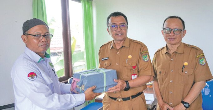 Kepala Dinas Perpustakaan dan Kearsipan Kabupaten Barito Utara, Fakhri Fauzi (Tengah) bersama Pustakawan Ahli Muda, Firdaus saat menerima hibah Al-Qur’an tulis tangan dari ahli waris, H. Afuw Anwar di KUA Kecamatan Teweh Tengah belum lama ini.