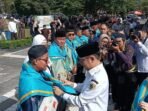Wali Kota Palangka Raya, Fairid Naparin mengalungkan slayer kepada salah satu jemaah haji kloter lima, di halaman Kantor Wali Kota Palangka Raya, Rabu pagi (29/4).