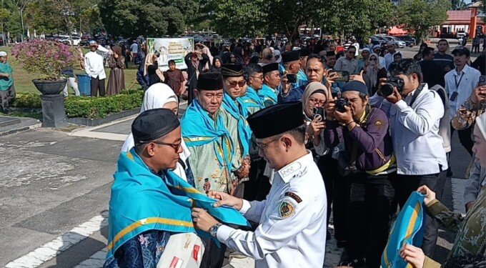 Wali Kota Palangka Raya, Fairid Naparin mengalungkan slayer kepada salah satu jemaah haji kloter lima, di halaman Kantor Wali Kota Palangka Raya, Rabu pagi (29/4).