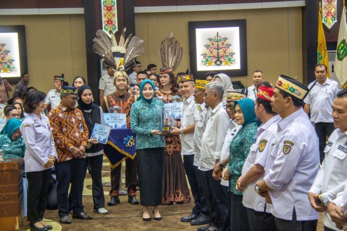 Ketua TP PKK Kalteng Aisyah Thisia Agustiar Sabran memberikan piala kepada Bupati Gunung Mas Jaya S Monong karena dinilai unggul dalam aspek konvergensi program saat Rakorda di Aula Jayang Tingang Lantai II, Rabu (29/4).