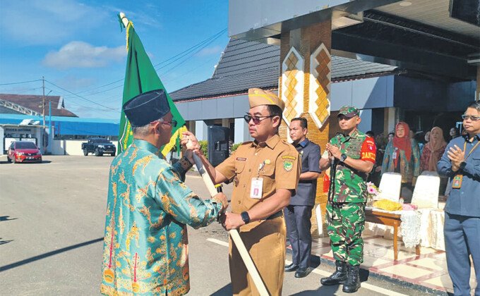 Asisten I Bidang Pemerintahan dan Kesra, Everiady Noor SE secara simbolis menyerahkan Pataka kepada Kepala Dinas Kebudayaan, Pariwisata, Kepemudaan, dan Olahraga sekaligus Ketua Kontingan Kabupaten Barito Utara pada FBIM Kalteng 2026, Pariadi AR pada acara Pelepasan di Halaman Kantor Bupati Barito Utara, Selasa (12/5).