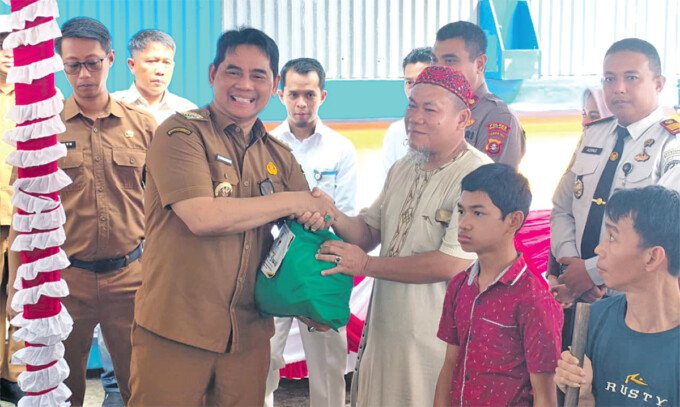 Barito Utara Bupati Barito Utara H Shalahuddin ST MT secara simbolis memberikan bantuan sosial kepada salah satu penerima pada acara Launching Bantuan Sosial Program Bantuan Sosial dan Honorarium Kelembagaan bagi Damang Adat, Mantir, dan RT/RW se-Kabupaten di Halaman Gudang Bulog, Muara Teweh, Senin (22/6).